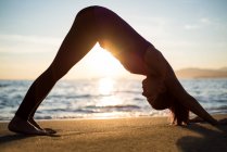 Вид збоку жінки, що здійснює йога на пляжі під час заходу сонця — стокове фото