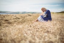 Surface level of beautiful blonde woman sitting in field — Stock Photo