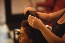 Mujer consiguiendo pelo alisado en peluquería - foto de stock