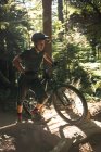 Male cyclist walking with mountain bike in forest — Stock Photo