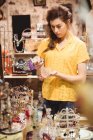 Femme regardant stand de bougie en verre dans un magasin d'antiquités — Photo de stock