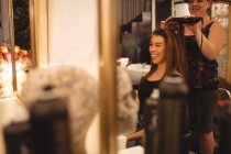 Mulher sorrindo ao obter cabelo endireitado no salão de cabeleireiro — Fotografia de Stock