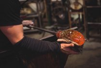 Cropped image of Glassblower shaping molten glass piece with wet cloth at glassblowing factory — Stock Photo
