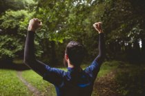 Excited athlete clenching his fists in forest — Stock Photo