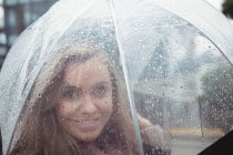 Retrato de una hermosa mujer sosteniendo el paraguas durante la temporada de lluvias en la calle - foto de stock