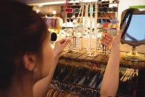 Стильная женщина выбирает украшения в антикварном ювелирном магазине — стоковое фото