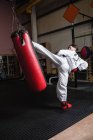 Back view of Man practicing karate with punching bag in fitness studio — Stock Photo