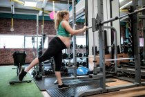 Беременная женщина упражняется с фитнес-бар в тренажерном зале — стоковое фото