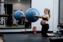 Femme enceinte faisant de l'exercice avec une balle de fitness au gymnase — Photo de stock