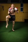 Boxeador tailandés musculoso sin camisa practicando boxeo en el gimnasio - foto de stock