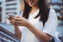 Mensajería de texto de mujer sonriente en el teléfono móvil - foto de stock
