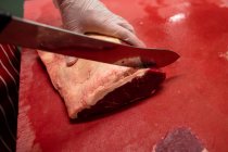 Рука мясника режет мясо в мясной лавке — стоковое фото