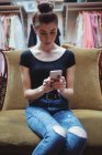 Woman using mobile phone in armchair in boutique store — Stock Photo