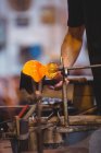 Mid section of glassblower forming and shaping a molten glass at glassblowing factory — Stock Photo