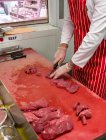 Mid section of butcher chopping red meat at butchers shop — Stock Photo