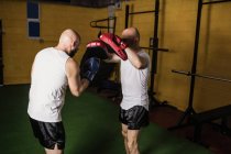 Vue latérale de deux boxeurs thaïlandais pratiquant la boxe dans la salle de gym — Photo de stock