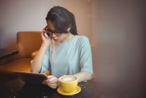 Junge Frau telefoniert im Café mit digitalem Tablet — Stockfoto
