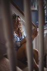 Schöne Frau, die auf der Treppe sitzt und zu Hause das Handy benutzt — Stockfoto