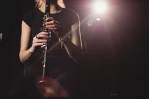 Mi-section d'une étudiante jouant de la clarinette dans un studio — Photo de stock