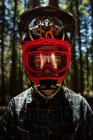 Portrait of male cyclist in helmet and goggles standing in forest — Stock Photo
