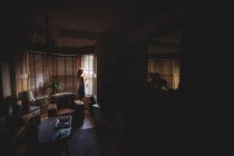 Frau schaut durch Fenster im heimischen Wohnzimmer — Stockfoto