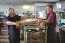 Склоочисник і колега, що тримає дерев'яний контейнер на скляній фабриці — стокове фото
