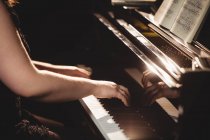 Mi-section de la femme jouant un piano dans un studio de musique — Photo de stock