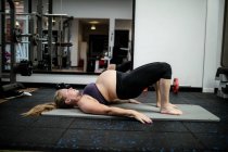 Femme enceinte effectuant des exercices d'étirement dans la salle de gym — Photo de stock