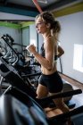 Schöne Frau trainiert auf Laufband im Fitnessstudio — Stockfoto