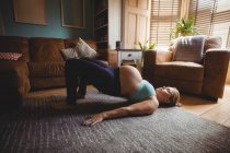 Вид збоку Вагітна жінка виконує розтяжку вправи у вітальні вдома — стокове фото
