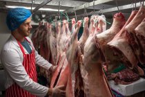 Boucher suspendu viande rouge dans la salle de stockage à la boucherie — Photo de stock
