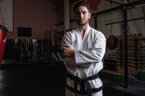 Retrato de homem bonito em karategi de pé com os braços cruzados no estúdio de fitness — Fotografia de Stock