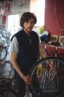 Retrato do mecânico que examina a bicicleta na oficina — Fotografia de Stock