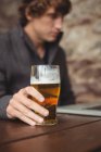 Uomo che beve birra mentre usa il computer portatile al bar — Foto stock