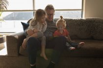 Grand-père et petite-fille utilisant une tablette numérique dans le salon à la maison — Photo de stock