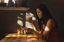 Seitenansicht einer Frau, die während eines Kaffees im Café ihr Handy benutzt — Stockfoto