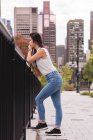 Seitenansicht einer Frau, die sich an einem sonnigen Tag an ein Geländer lehnt — Stockfoto