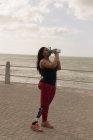 Вид збоку жінки з обмеженими можливостями, що п'є воду на набережній — стокове фото