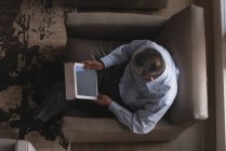 La sobrecarga del hombre mayor usando tableta digital en la sala de estar en casa - foto de stock