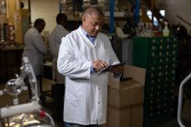 Trabajador masculino usando tableta digital en fábrica de vidrio - foto de stock
