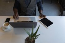 Средний раздел бизнесмена, использующего ноутбук и цифровой планшет в офисе — стоковое фото