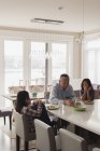 Grandfather and granddaughters having food on dining table at home — Stock Photo