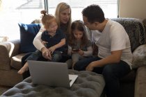 Famiglia che interagisce tra loro sul divano in soggiorno a casa — Foto stock
