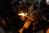 Крупним планом працівник використовує зварювальний факел на скляному заводі — стокове фото