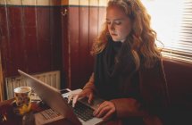 Рыжая женщина использует ноутбук в кафе — стоковое фото