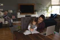 Father helping his daughter in studies in living room at home — Stock Photo