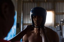 Trainer unterstützt männliche Boxer beim Tragen von Kopfbedeckungen im Boxclub — Stockfoto