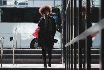 Mujer joven hablando por teléfono móvil mientras camina en la ciudad - foto de stock