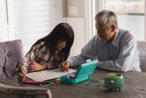 Grandfather and granddaughter drawing sketch on dining table at home — Stock Photo