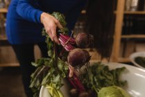 Partie médiane de la femme cueillette de légumes dans le panier au supermarché — Photo de stock